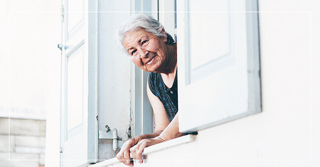 Ältere glückliche Frau am Fenster