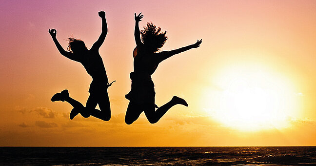 zwei junge Personen machen Luftsprung im Sonnenuntergang