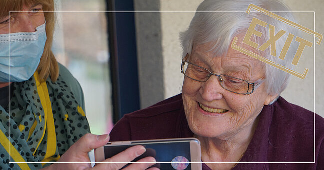Seniorin lässt sich von Pflegekraft Smartphone zeigen