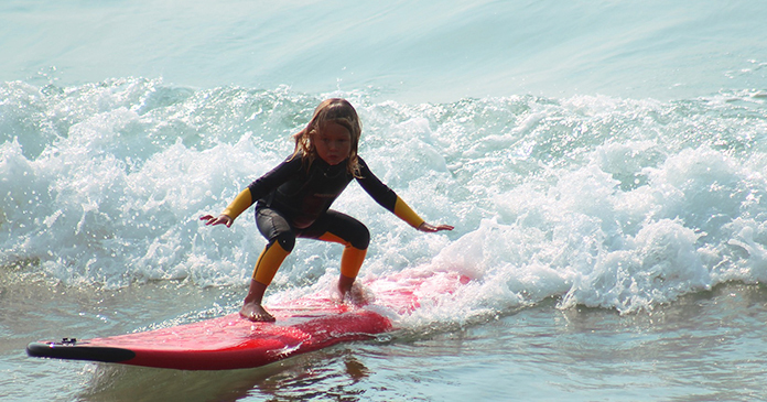 Kind auf rotem Surfboard auf Wellen